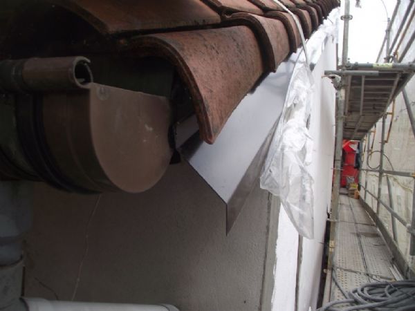 En fachada lateral; detalle de remate en z bajo teja, con pieza de aluminio lacado en marrón