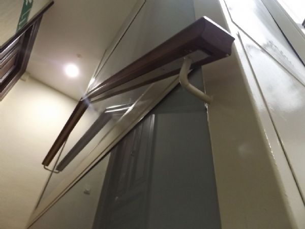 La obra y terminada, detalle de pasamanos de madera, sobre llanta de hierro y los laterales del ascensor con cristal opaco