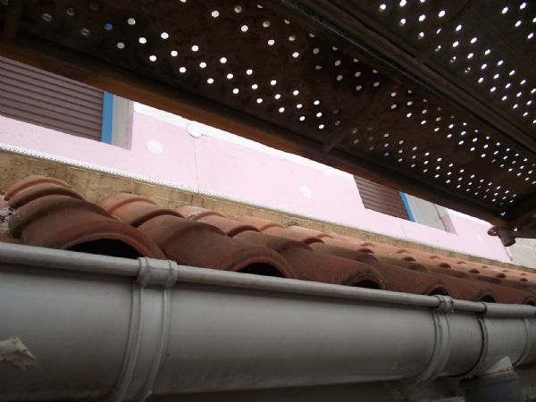 Colocación de placas de aislamiento de poliestireno extruido. Las placas rosas son las que se colocan en el encuentro con el suelo, suelos de balcones y sobre el tejado, por ser más resistentes a la humedad. También se observan los tapones que se han colocado sobre los anclajes.