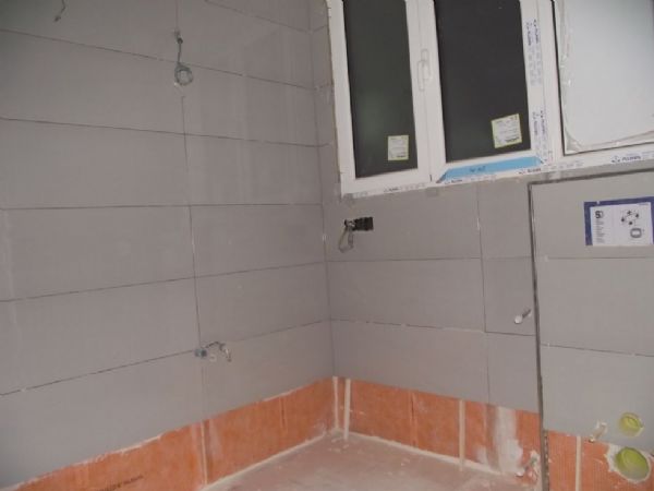 Las paredes del baño impermeabilizadas con la lamina de color naranja y en proceso de alicatado