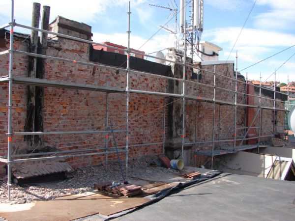 la fachada lateral derecha. Se puede observar como se han colocado tableros bajo el andamio, para evitar daar la cubierta del edifico colindante sobre la que se apoya el andamio. En la zona central el andamio queda sin apoyar, por estar el lucernario del patio.