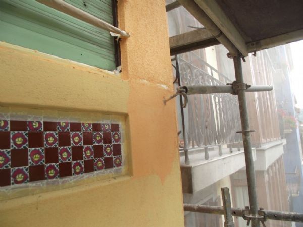 La fachada principal con la pintura de fondo aplicada y aplicando el mortero acrilico